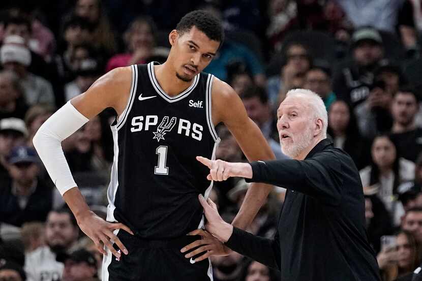 San Antonio Spurs head coach Gregg Popovich, right, talks with center Victor Wembanyama (1)...