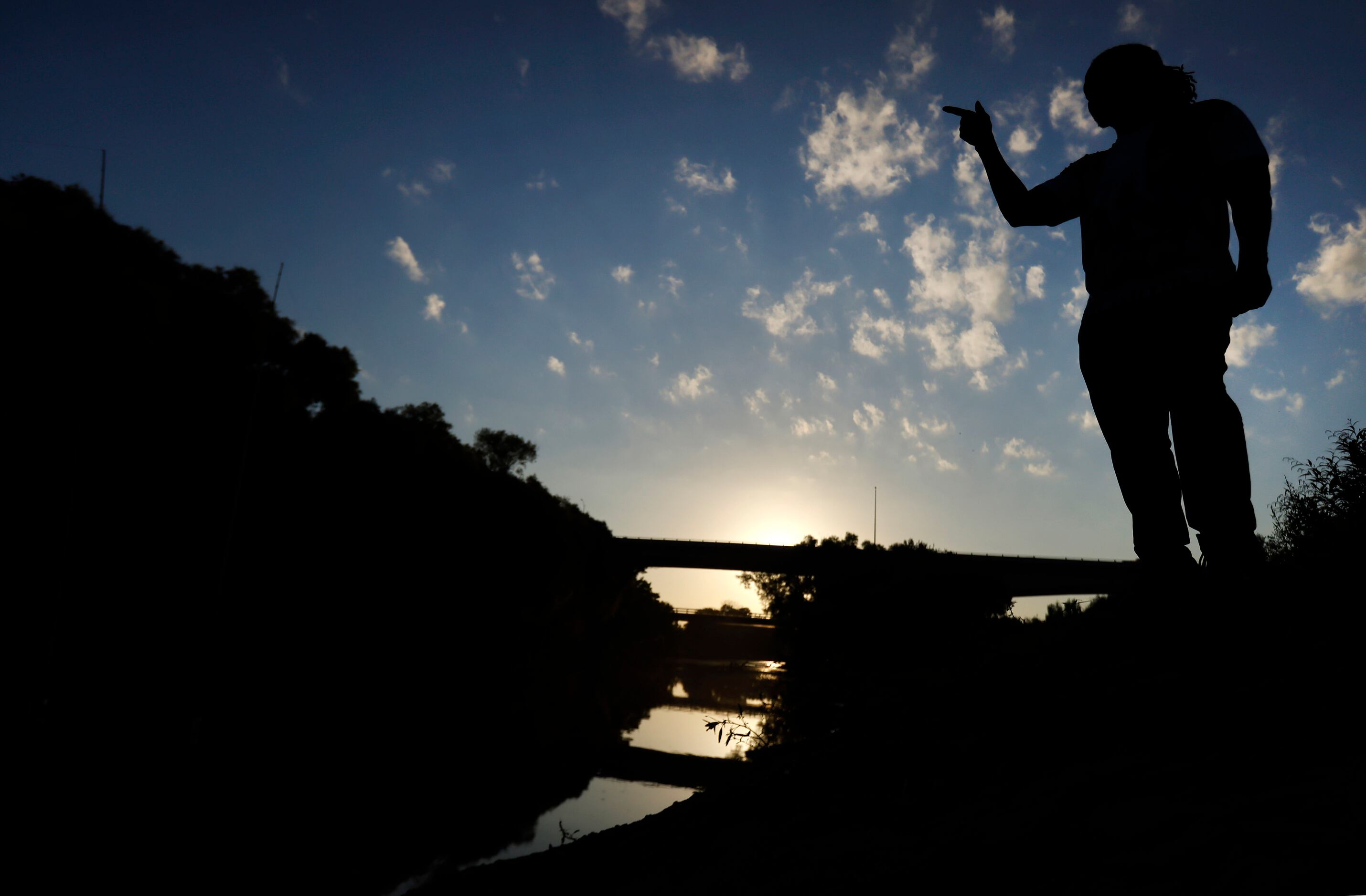 Odell Allen watches his lines as he fishes for alligator gar in the Trinity River near the...