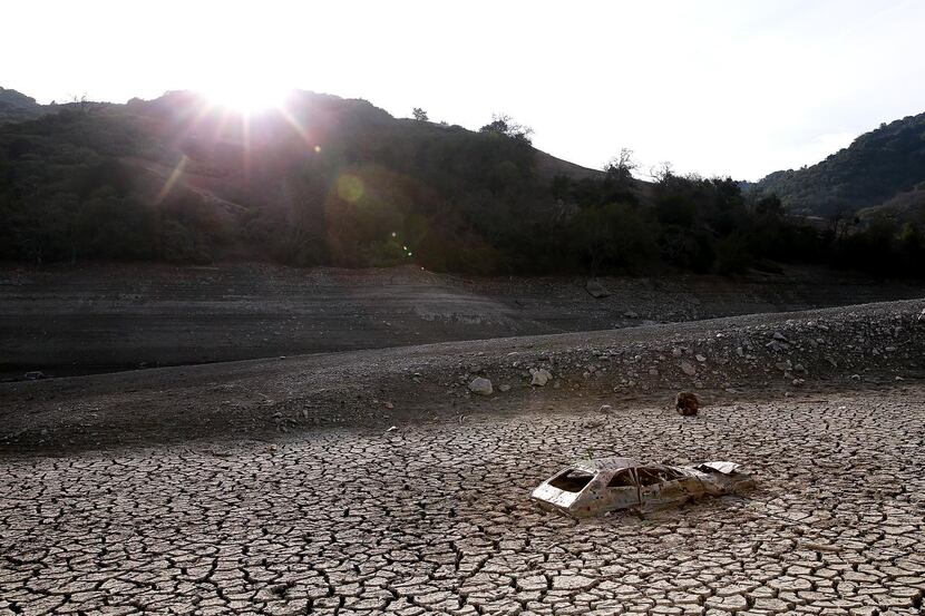 
A car sits in dried and cracked earth of what was the bottom of the Almaden Reservoir in...