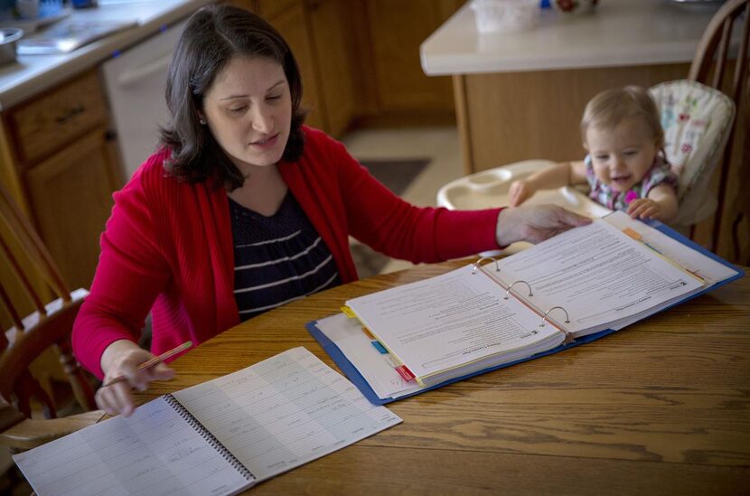 
Maria Kahlig (left) goes over upcoming lesson plans, while her 1-year-old daughter, Emily,...