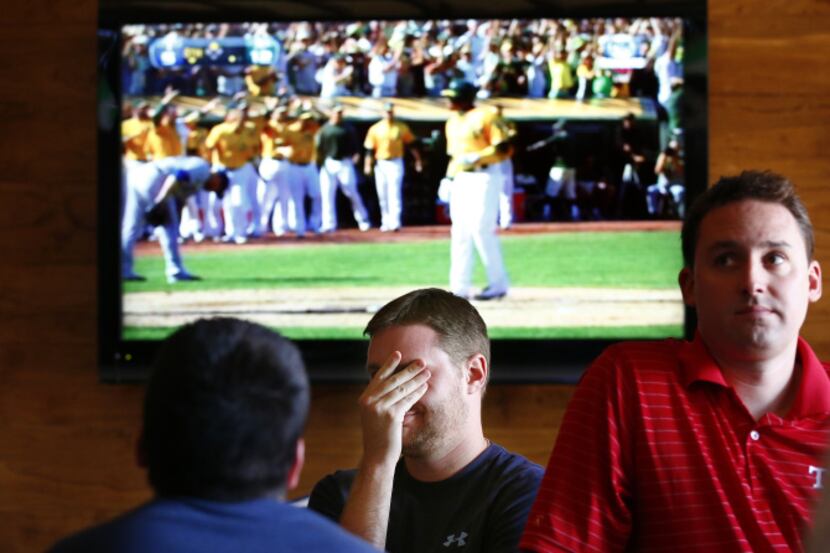 Rangers fan Mark Wagner (center) of Frisco couldn't bear to watch as the A's extended their...