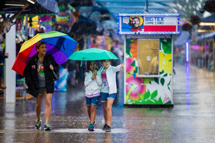 Julie Fernández, Catalina Fernández y Kariss Fernández se protejen de la lluvia el martes...
