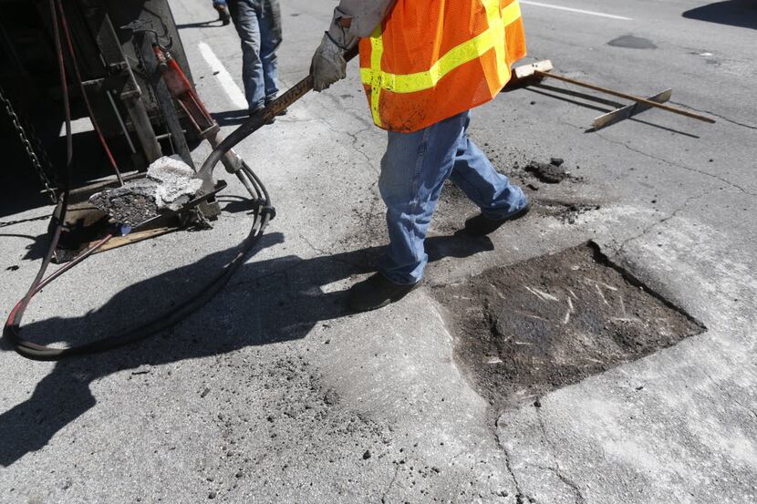 Dallas Street Services employees fix a pothole on Harry Hines Boulevard in Dallas. 