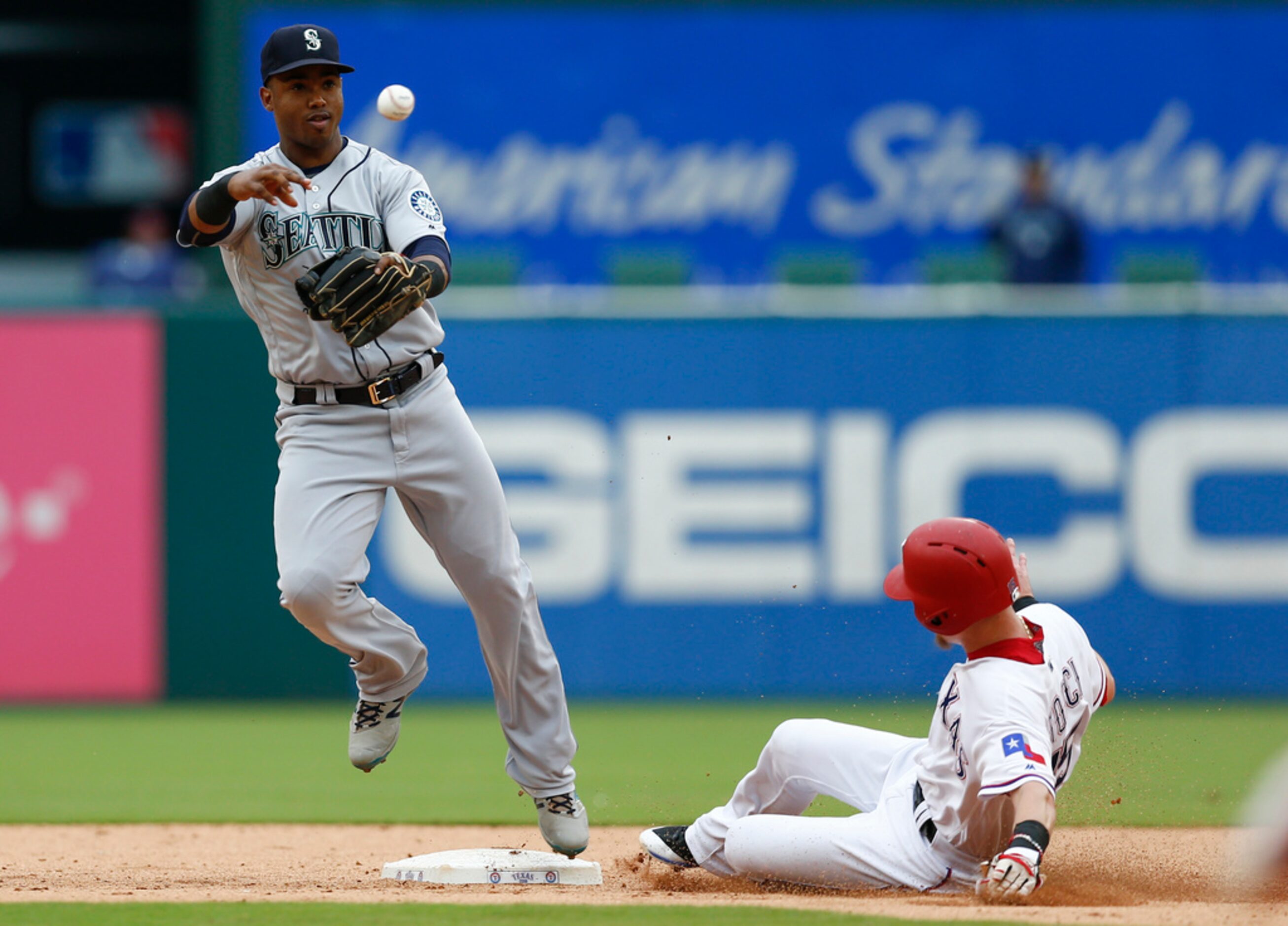 Seattle Mariners shortstop Jean Segura, left, throws to first base after forcing out Texas...