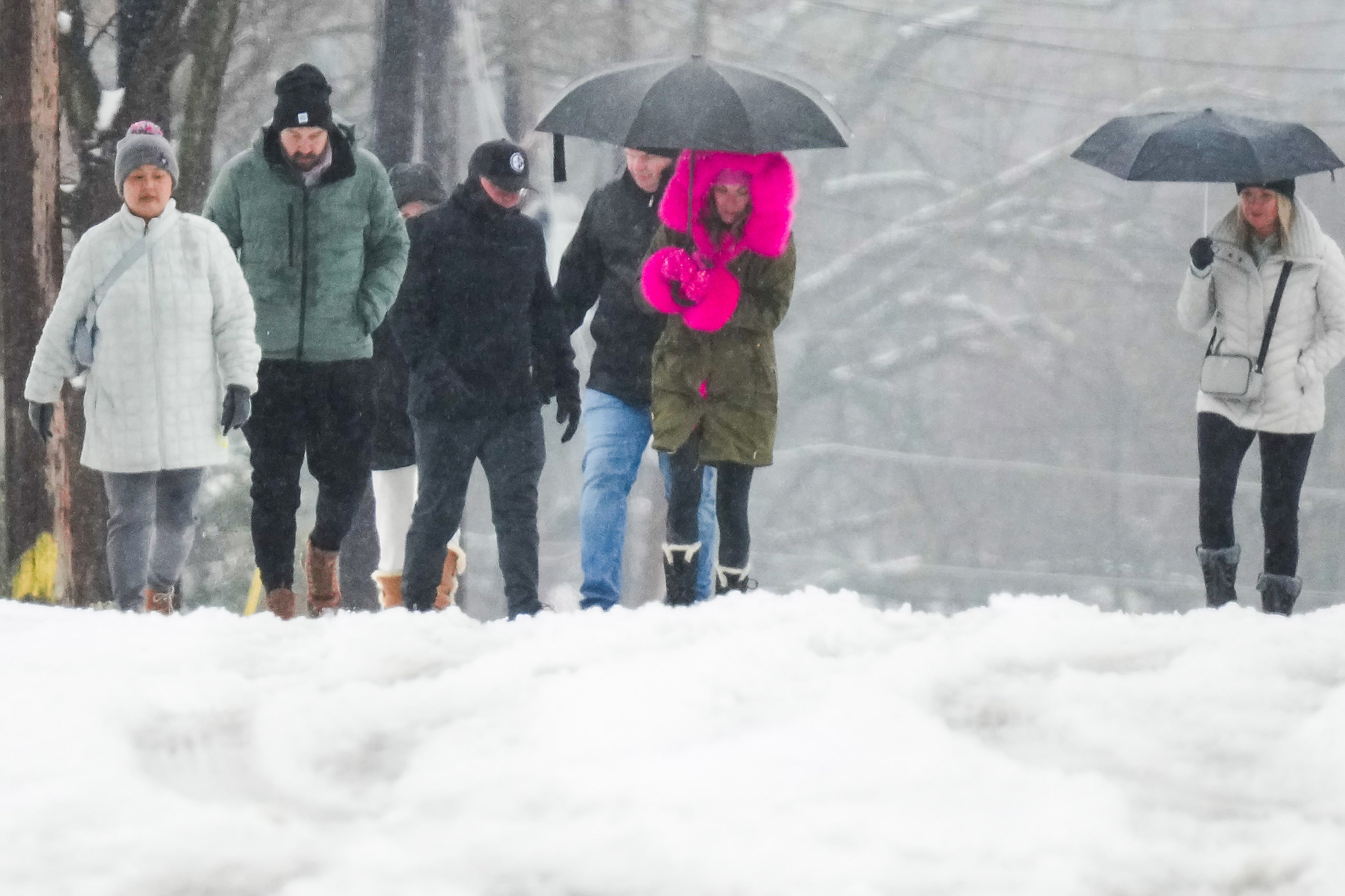 People walks along a snowy street on Thursday, Jan. 9, 2025, in McKinney.