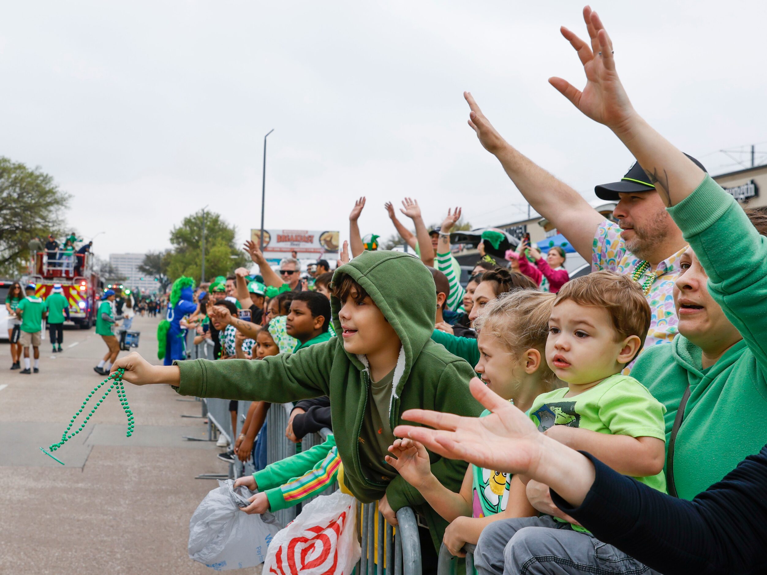 Attending crowd tries to catch green bead necklaces tossed by marchers during a Saint...