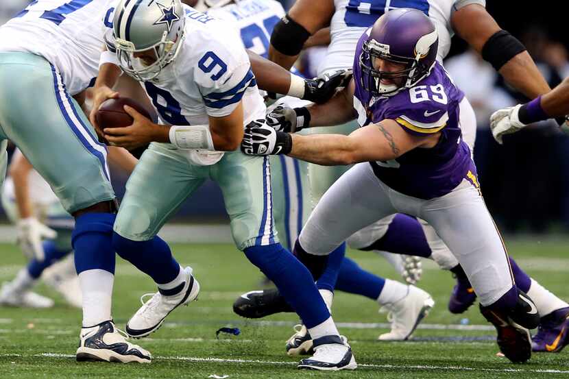 Dallas Cowboys quarterback Tony Romo (9) evades Minnesota Vikings defensive end Jared Allen...