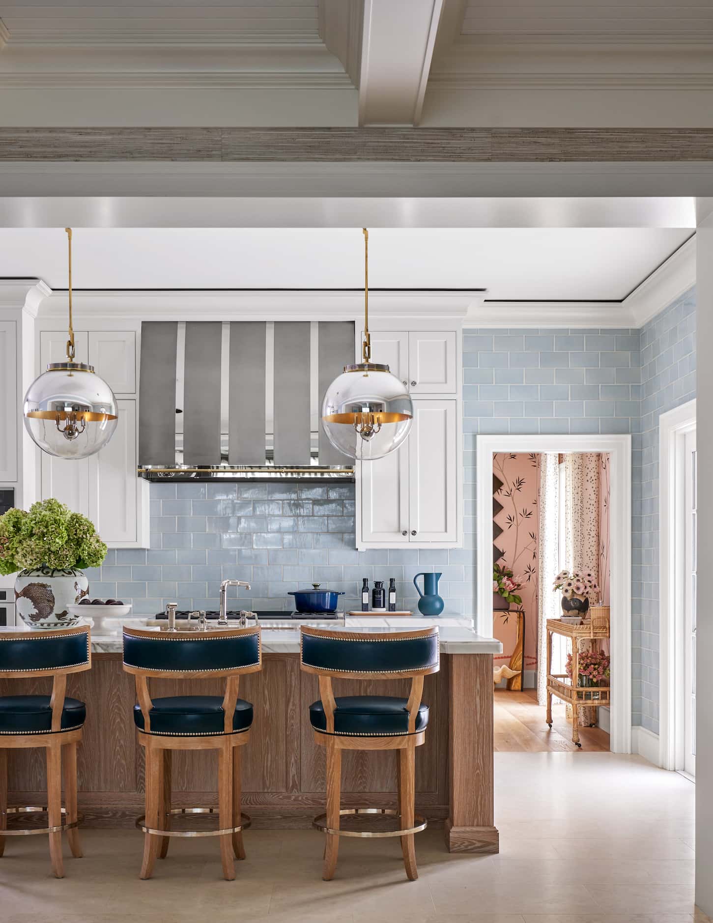 White kitchen with blue tile on walls, large center island and barstools