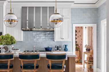 White kitchen with blue tile on walls, large center island and barstools