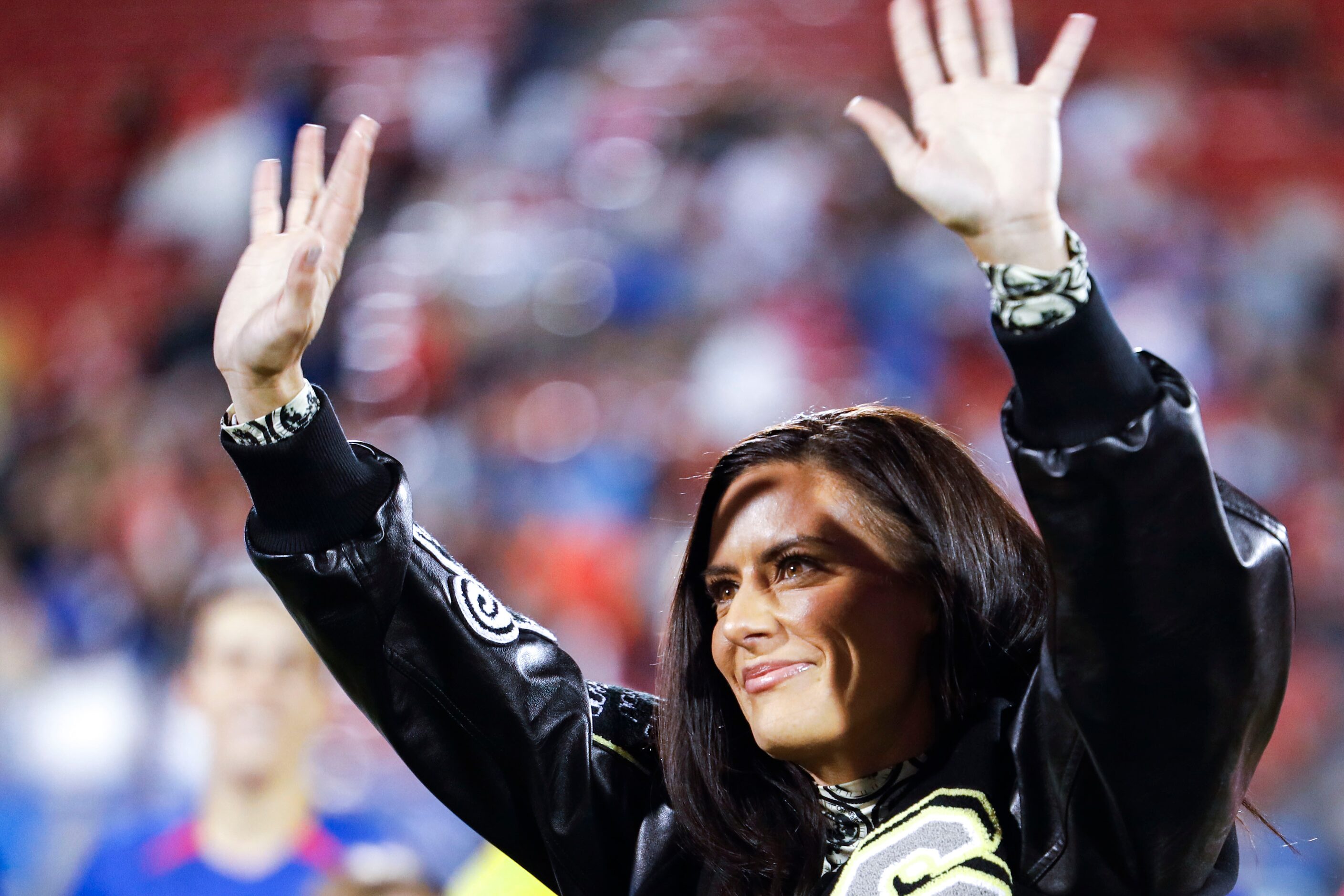 Former United States’ soccer player Ali Krueger waves towards the crowd as she was honored...