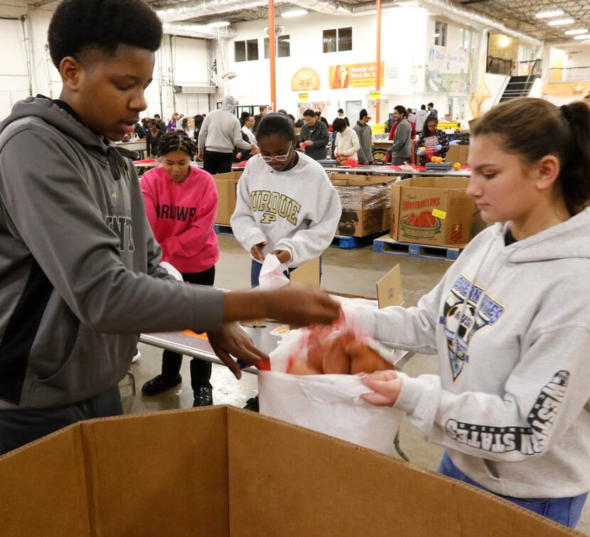 Volunteers George Babineaux, left, puts sweet potatoes in a bag for Isabella Szabo, right,...