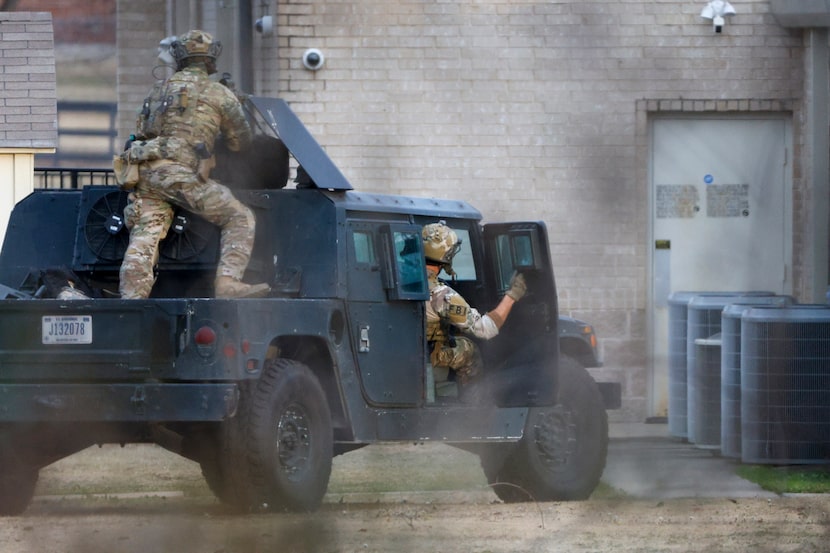 Members of the FBI watch an entrance on the rear of the building while conducting SWAT...