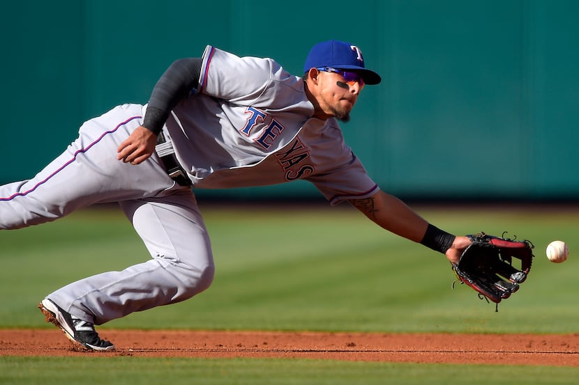 Texas Rangers second baseman Rougned Odor can't reach a ball hit for an RBI single by Los...