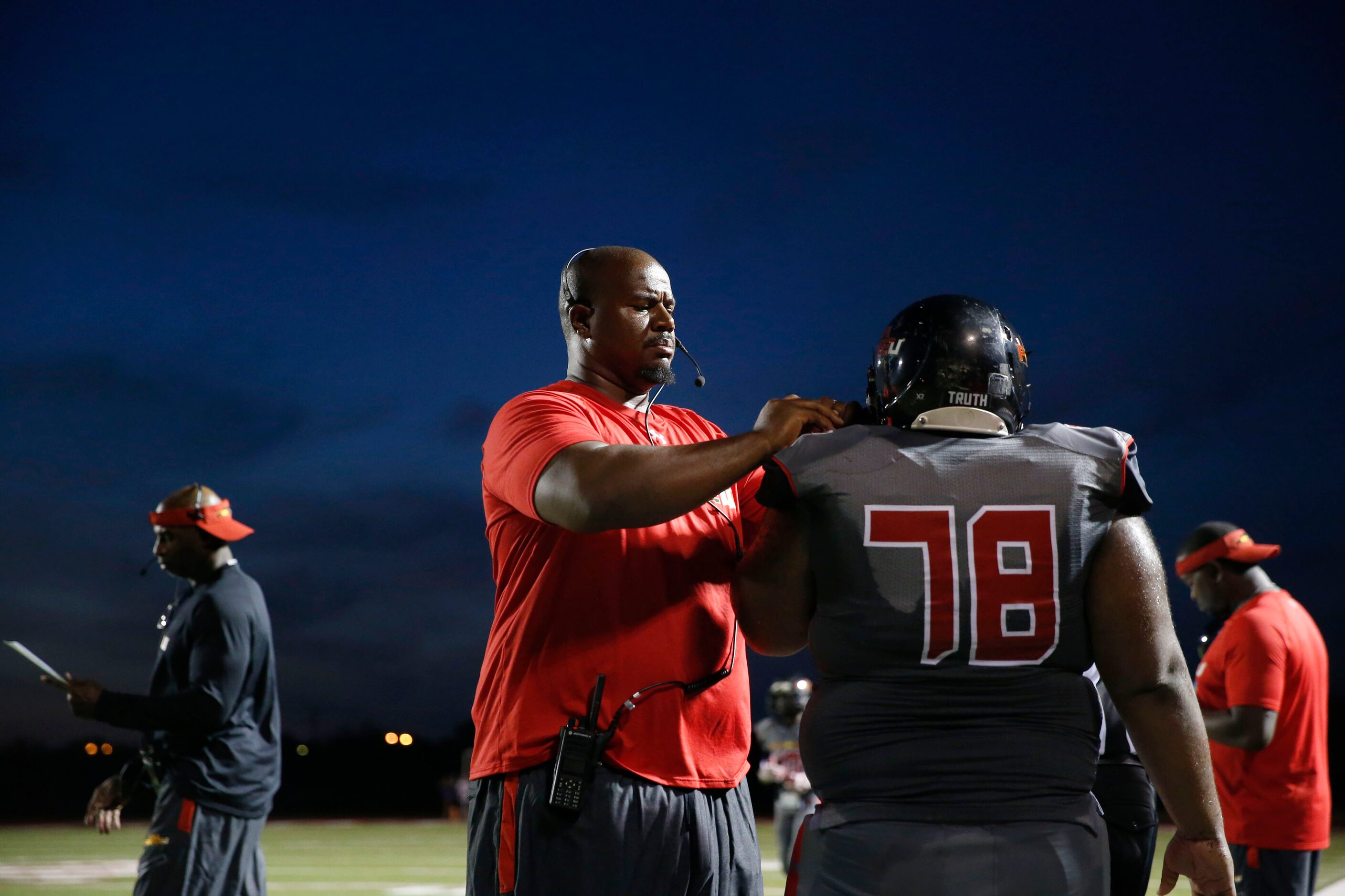 AAA Prime U line coach Ronald Redmond assists tackle Kedrick Smith with a helmet adjustment...