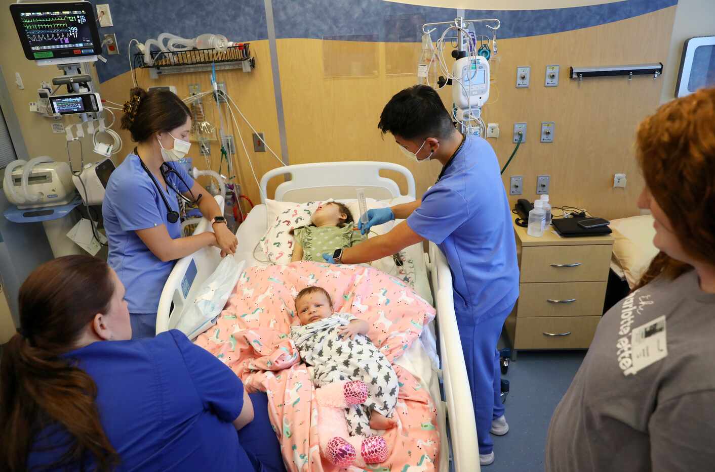 Rachel Miller (left), R.N., and Savan Nguyen, R.N., tend to Charlotte Brookes (center), 5,...