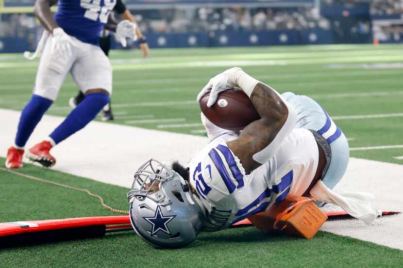 Dallas Cowboys running back Ezekiel Elliott (21) lands on a television camera pylon as he...