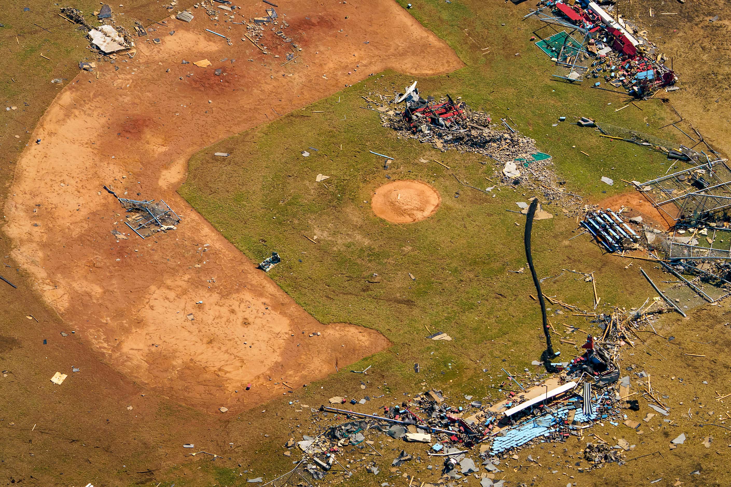 Debris from tornado damage is strewn across a baseball field at Thomas Jefferson High School...