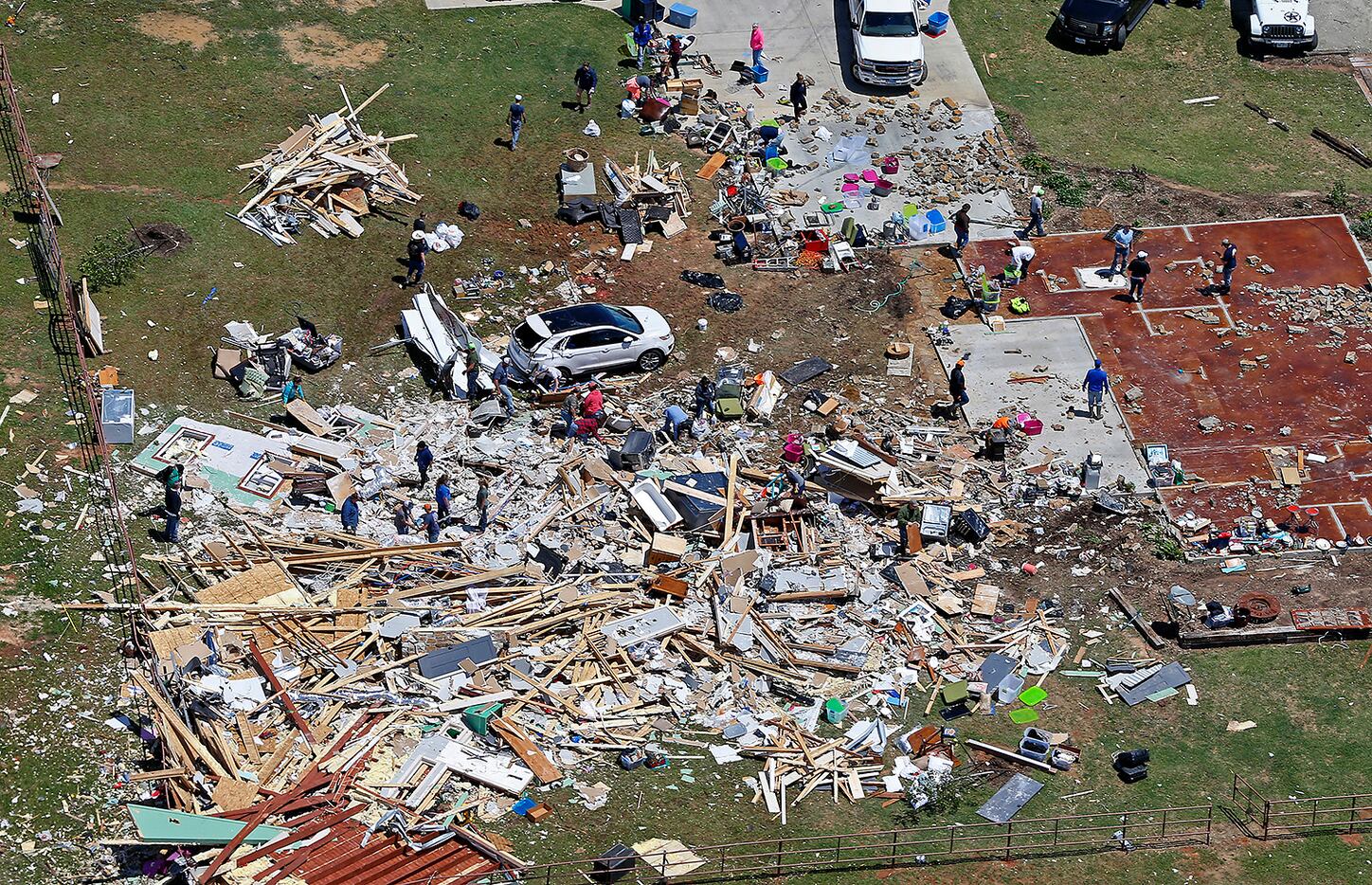 People clean up the debris at a house destroyed by yesterday's tornado in Canton, Texas,...