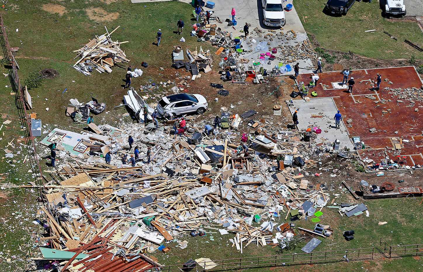 People clean up the debris at a house destroyed by yesterday's tornado in Canton, Texas,...