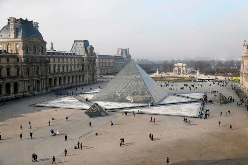 People walk around the pyramid of the Louvre, designed by Chinese-American architect I.M....