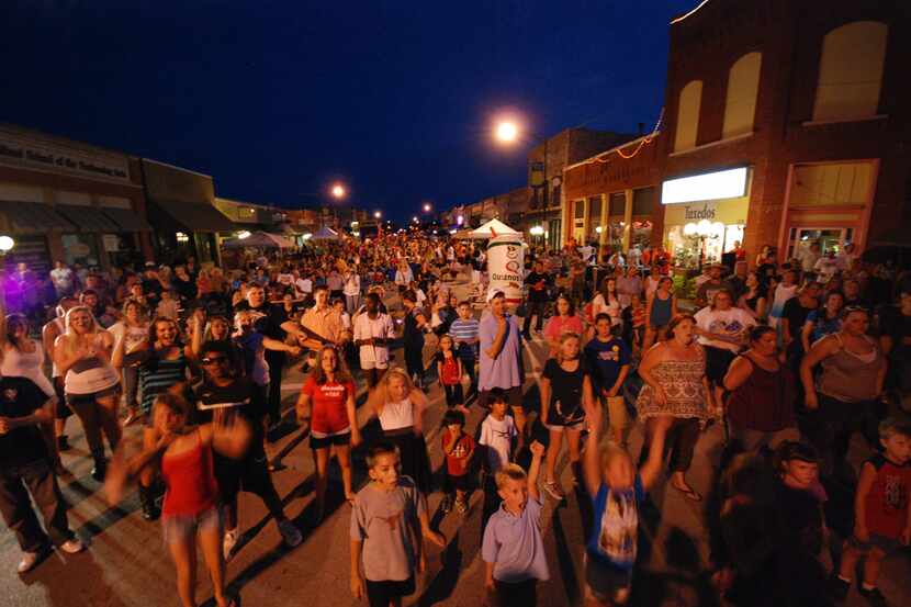 A large crowd dances in the street in historic downtown Wylie on Ballard Avenue during its...