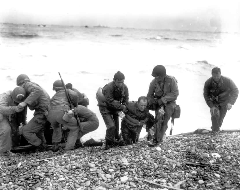 Members of an American landing unit help their exhausted comrades ashore at Utah Beach, near...