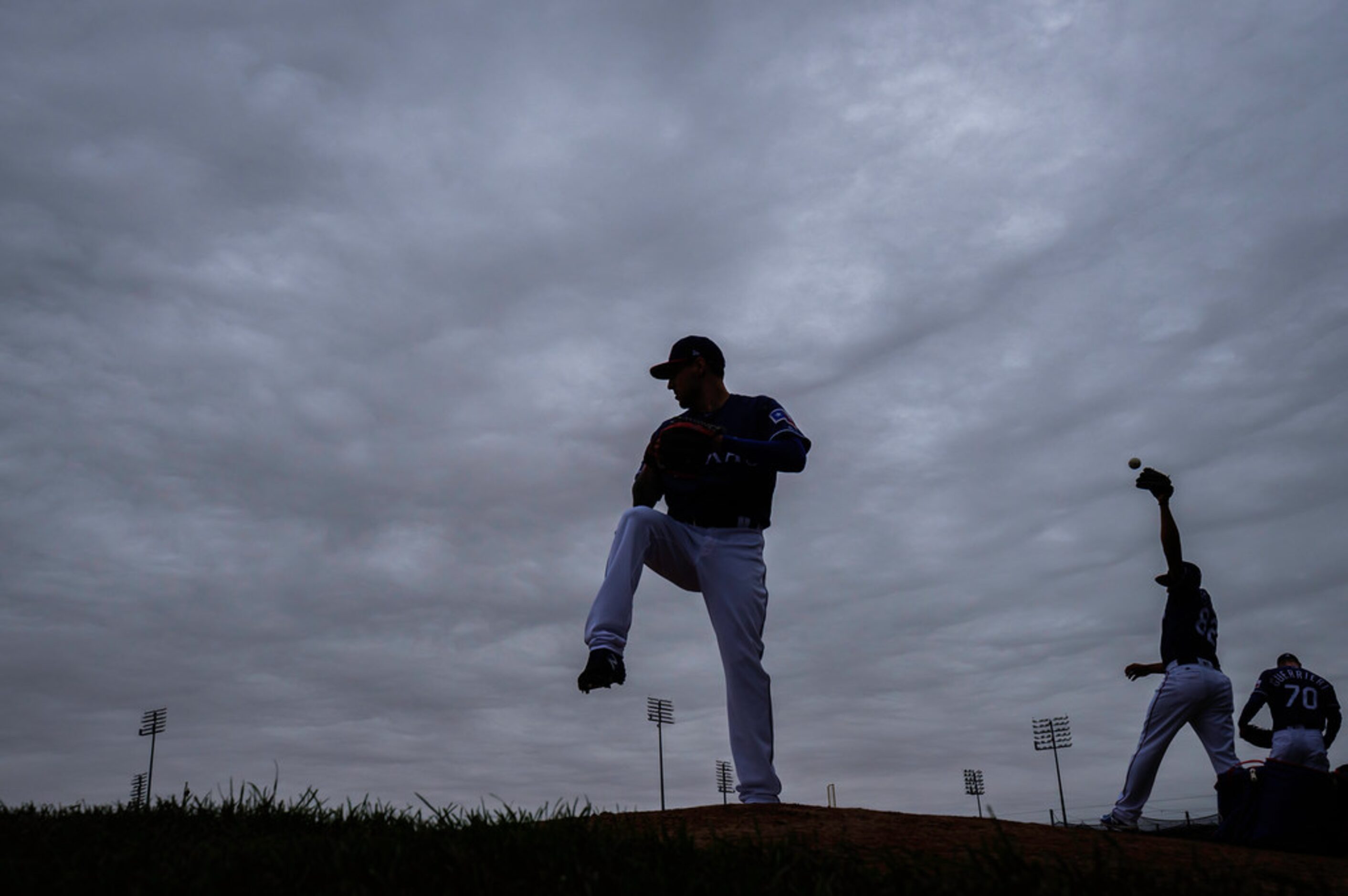 Texas Rangers pitcher Joe Palumbo throws a bullpen session in a light drizzle under heavy...