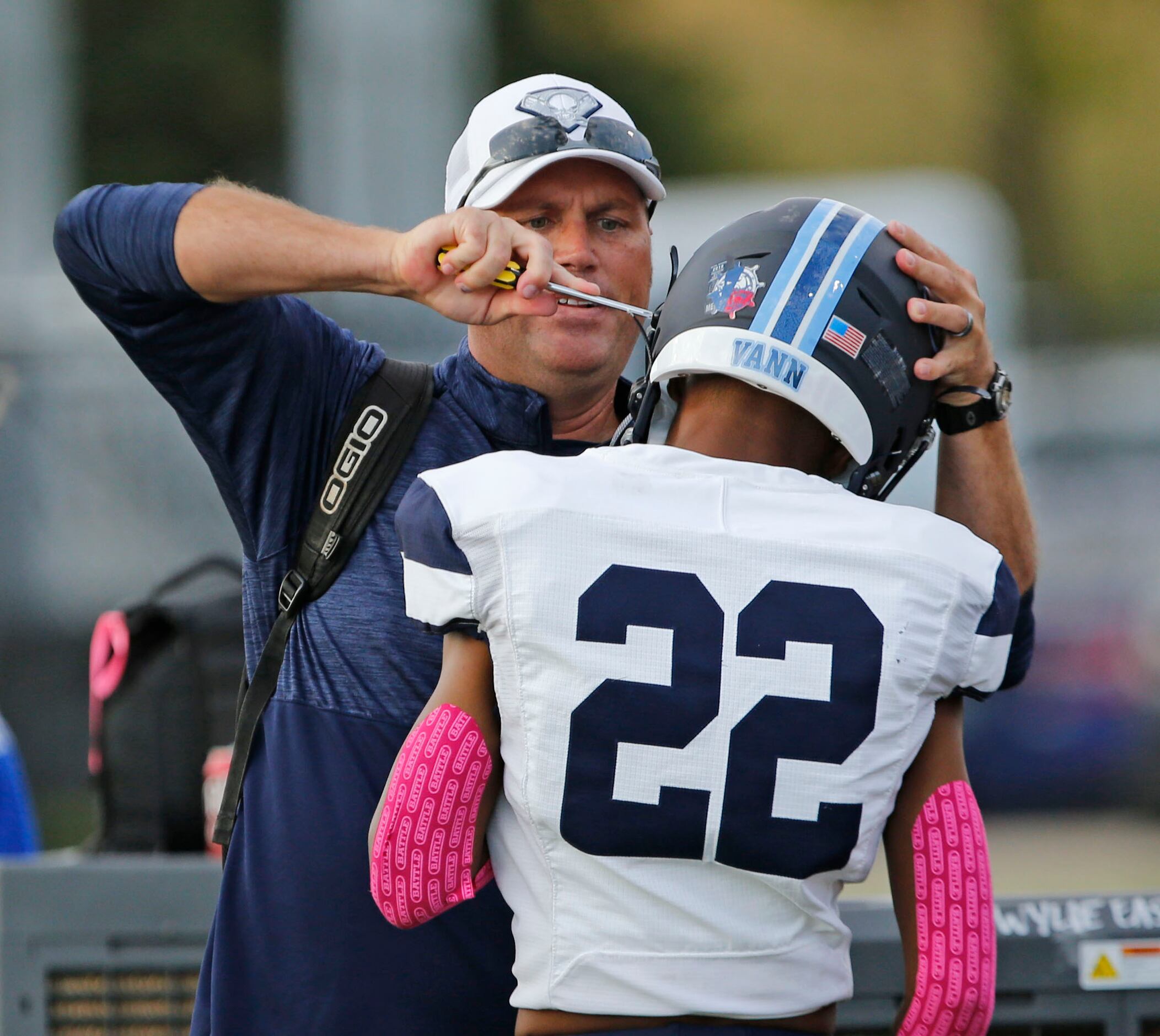 A Wylie East coach performs a helmet adjustment for player Jaxsen Vann (22) before the start...