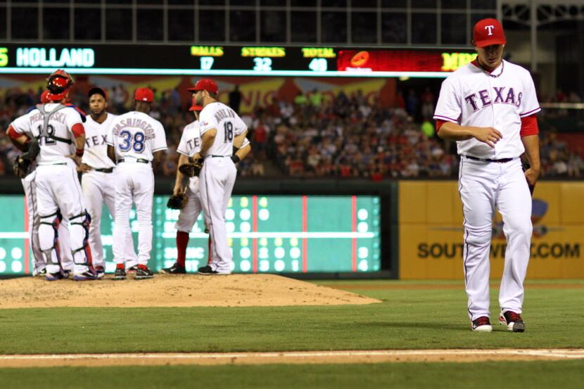 Texas Rangers starting pitcher Derek Holland leaves the field after being pulled by Rangers...