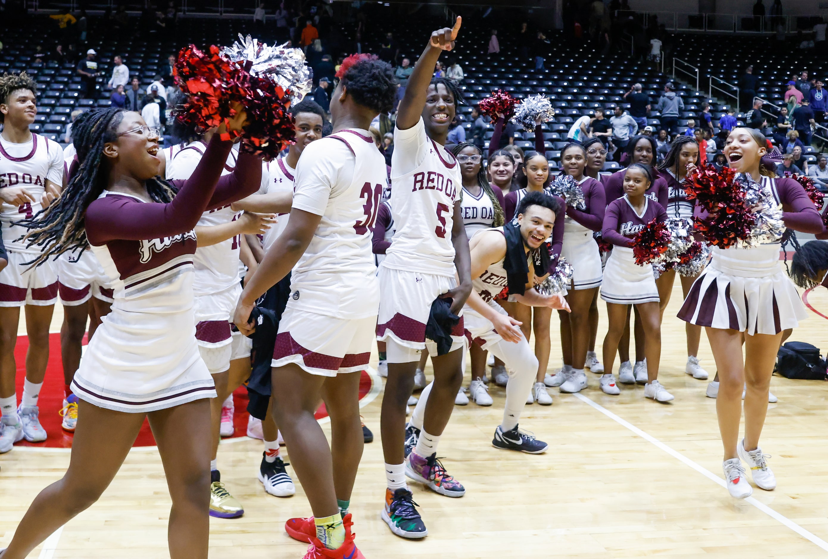 Red Oak junior guard Devin Boone (5, center) raises his hand to the crowd as senior guard...