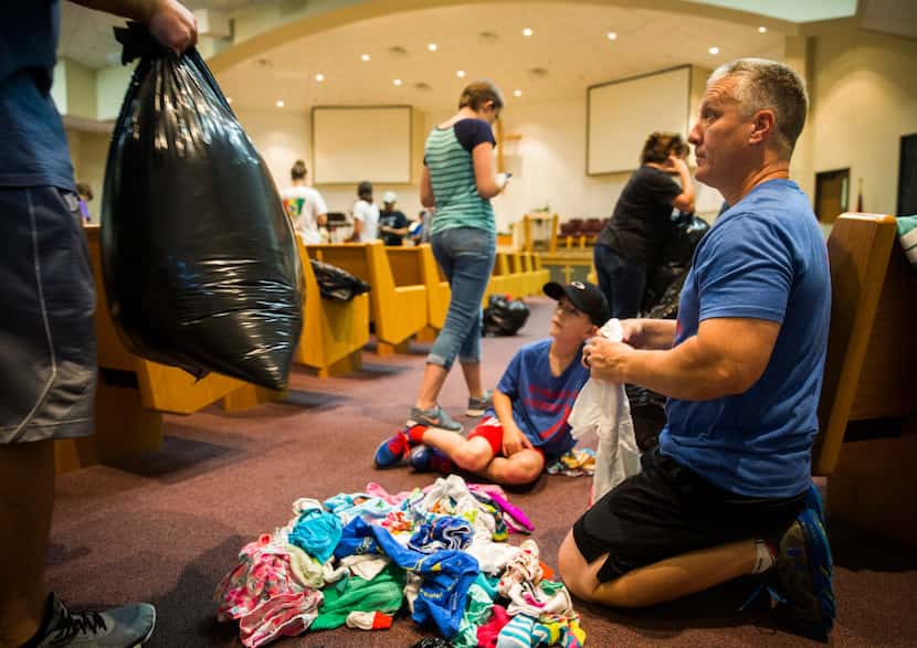 Tanner, 10, and Tab Burton and other volunteers fold donated clothes in a shelter at...