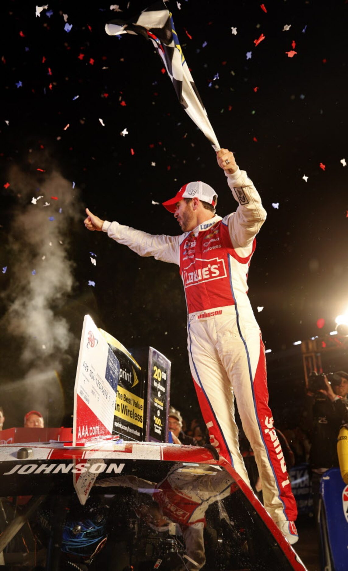 Sprint Cup Series driver Jimmie Johnson (48) stands on his car window as he celebrates his...