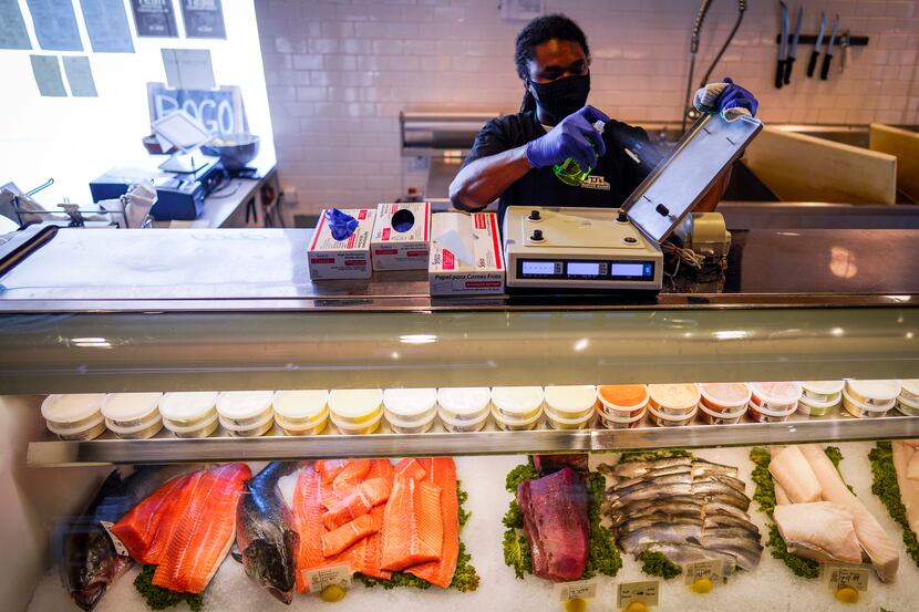 Zach Kennedy disinfects the scale at the fish counter at TJ's Seafood restaurant on Tuesday...