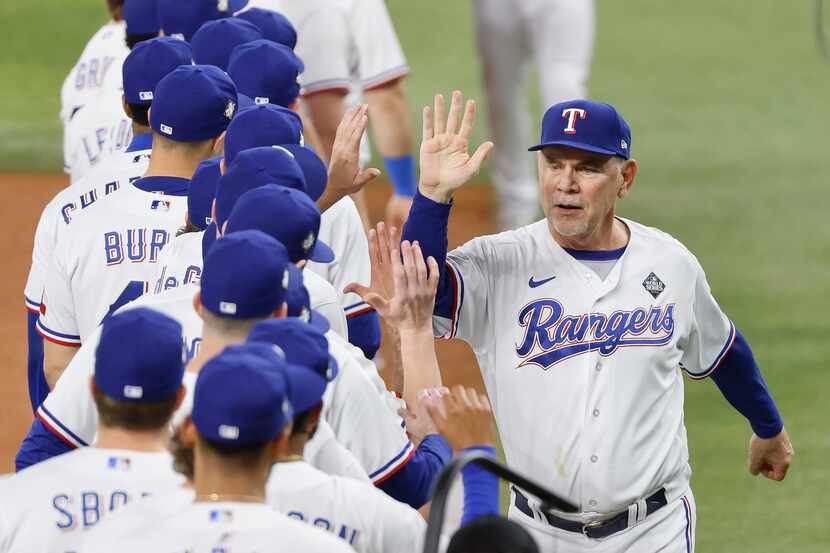 Texas Rangers manager Bruce Bochy high-fives his players after being introduced before Game...