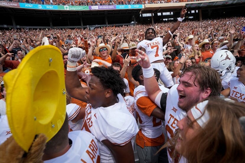 Texas players, including running back Keilan Robinson (7) celebrate with fans after a...