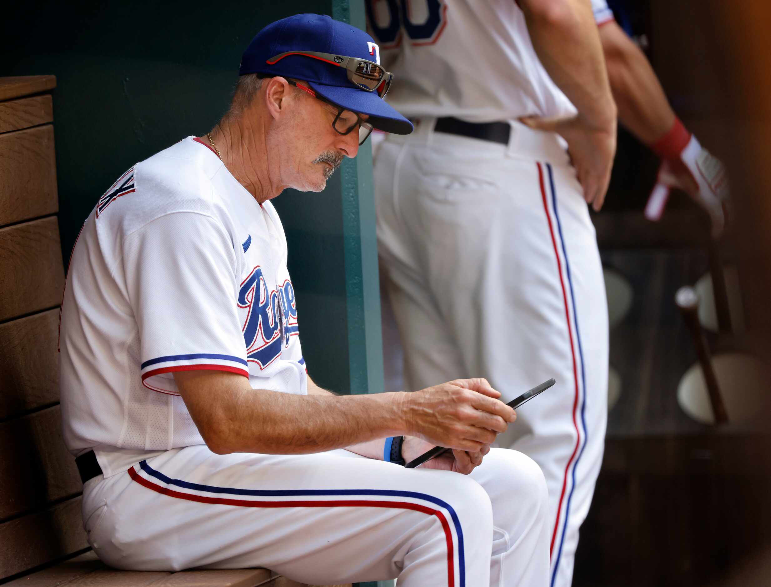 Texas Rangers pitching coach Mike Maddux looks over his tablet in the ninth inning against...