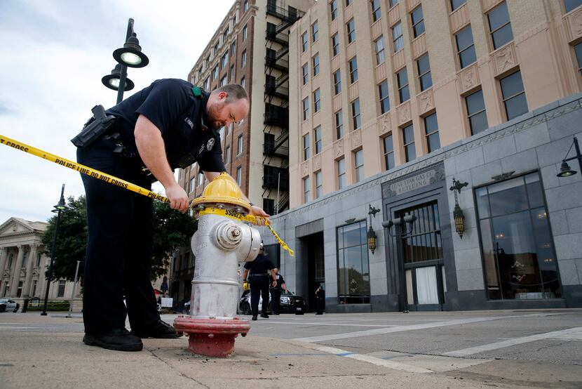 Dallas police string crime scene tape along Harwood St in downtown Dallas after shooting at...