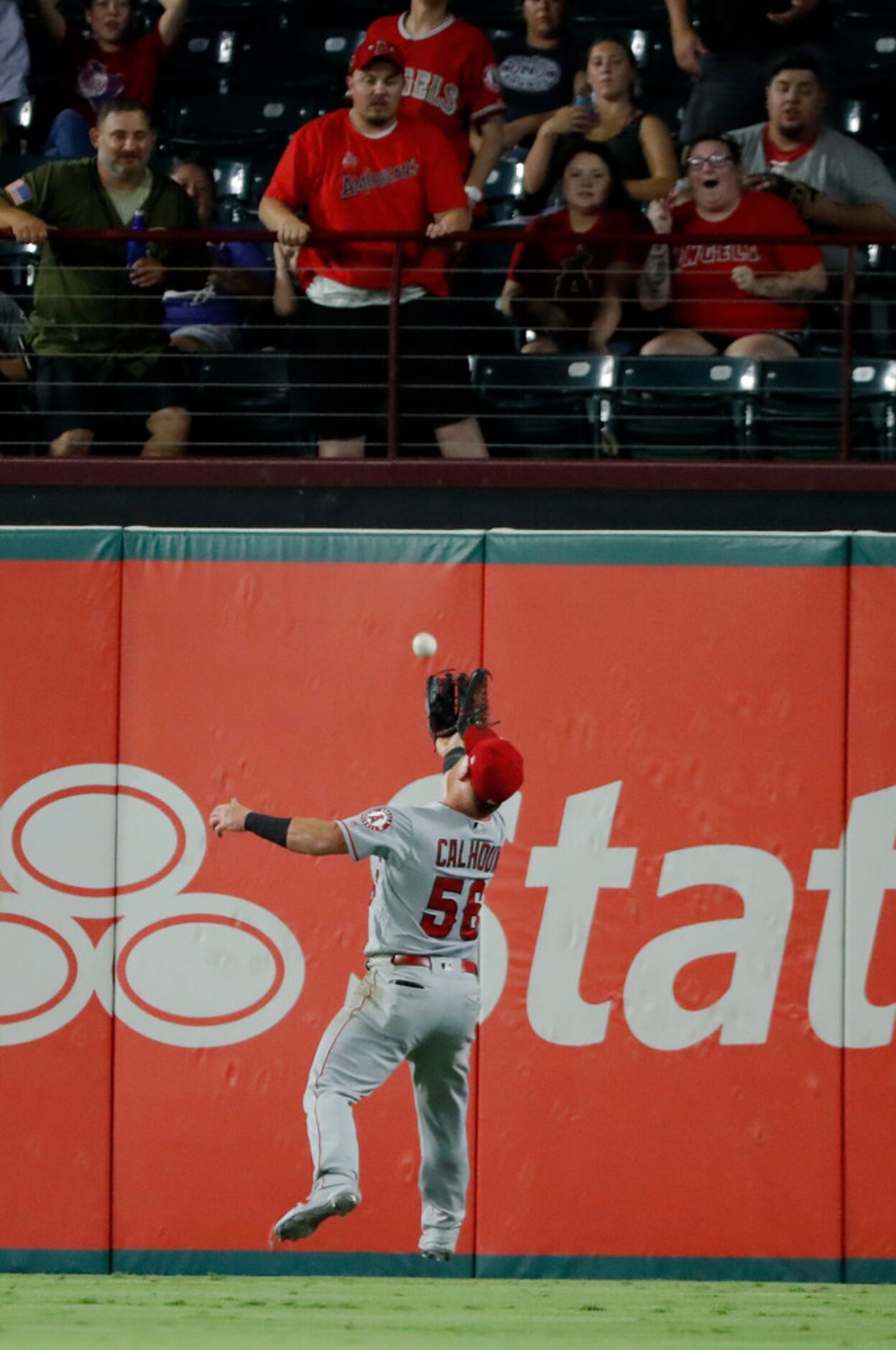 Fans look on s Los Angeles Angels right fielder Kole Calhoun makes a catch over his shoulder...