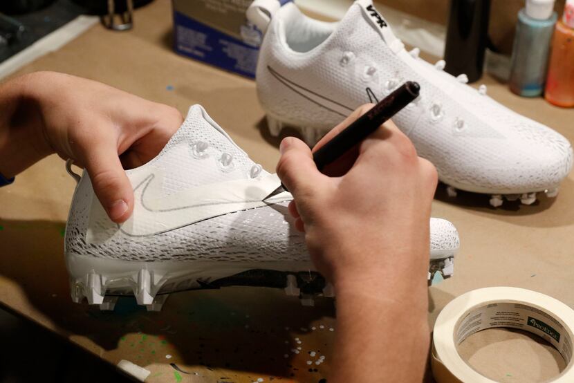 Luke Savage, 16, cuts out tape on cleats he's creating for SportsDayHS in his home in Dallas...