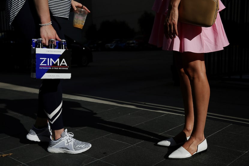 Caitlin Costa (left) and Olivia Simons, both of Dallas, speak along Commerce Street on July...