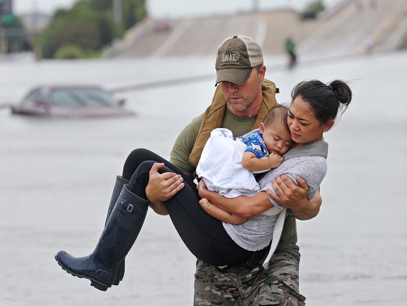 Houston SWAT officer Daryl Hudeck carries Catherine Pham and her 13-month-old son, Aiden, to...
