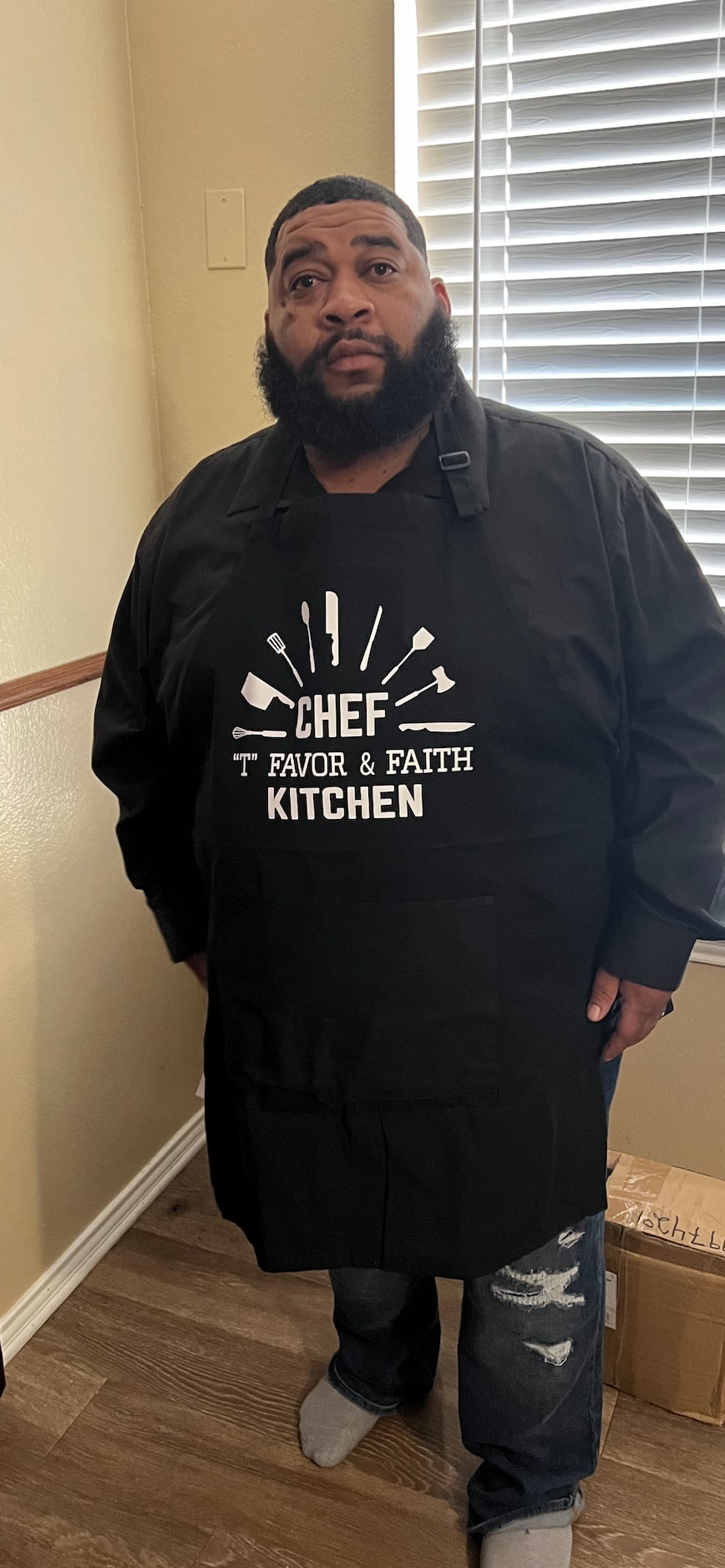 Terrell wearing his apron which reads "Chef 'T' Favor & Faith Kitchen."