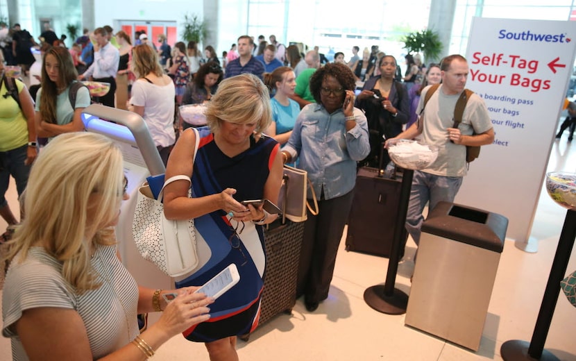 Passengers wait in line at the Southwest Airlines terminal at Dallas Love Field Airport in...