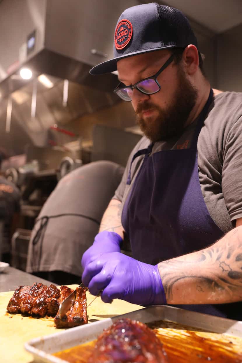 Chef de cuisine Josh Healy plates Loro's smoked baby back Duroc pork ribs after finishing...