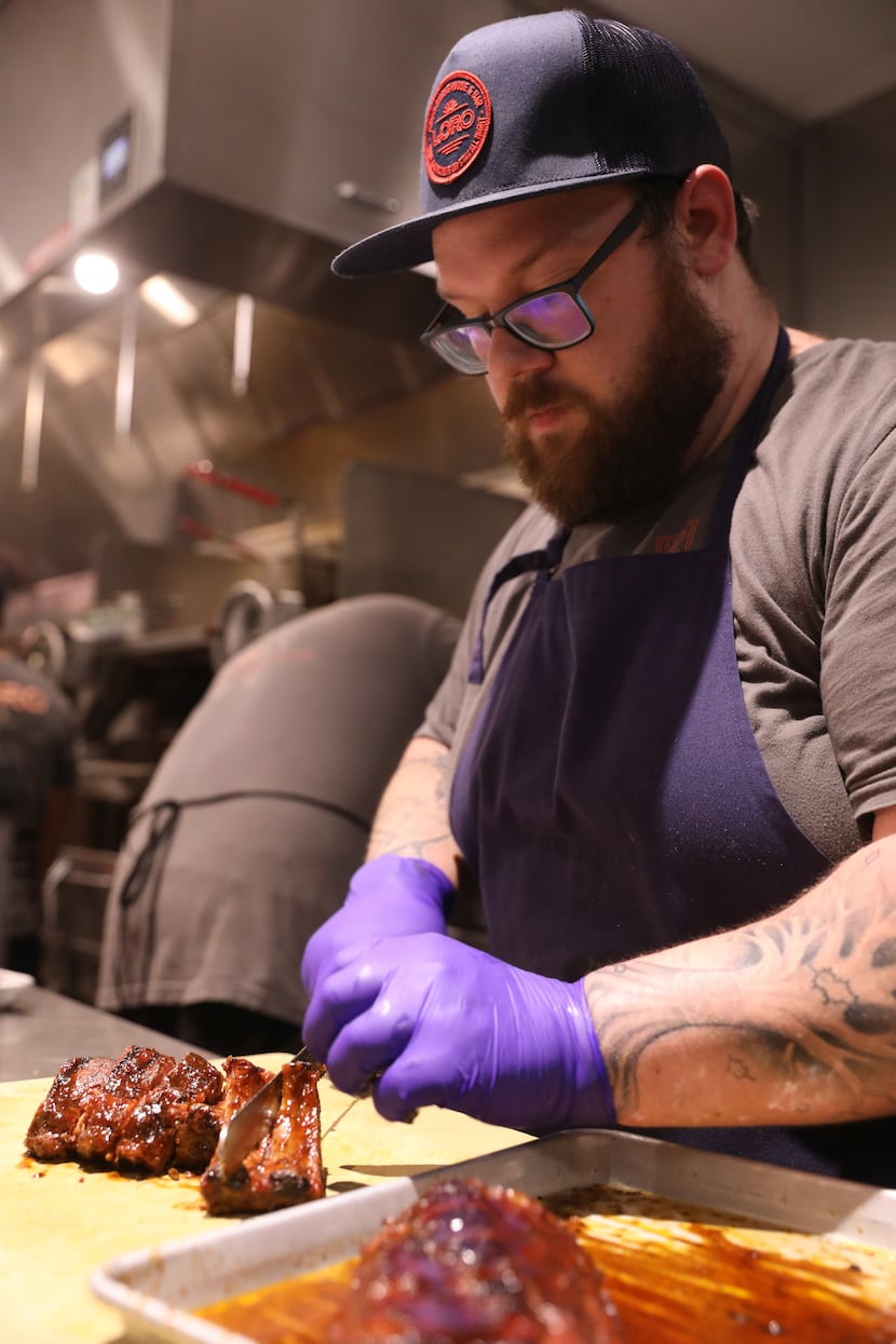 Chef de cuisine Josh Healy plates Loro's smoked baby back Duroc pork ribs after finishing...