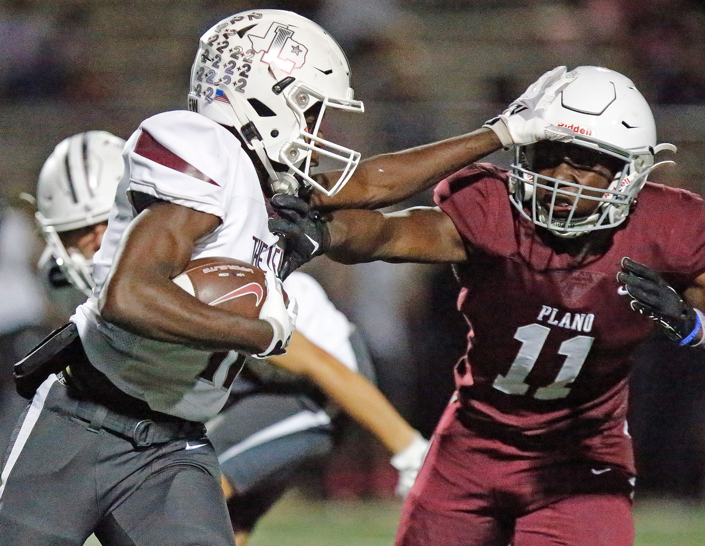 Lewisville High School running back Xavier Lewis (11) stiff arms Plano Senior High School...