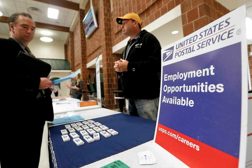 FILE- In this Nov. 2, 2017, file photo a recruiter from the postal service, right, speaks...