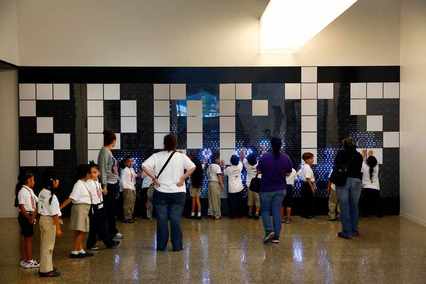School kids play with an interactive LED wall outside the sports hall on the lower level of...