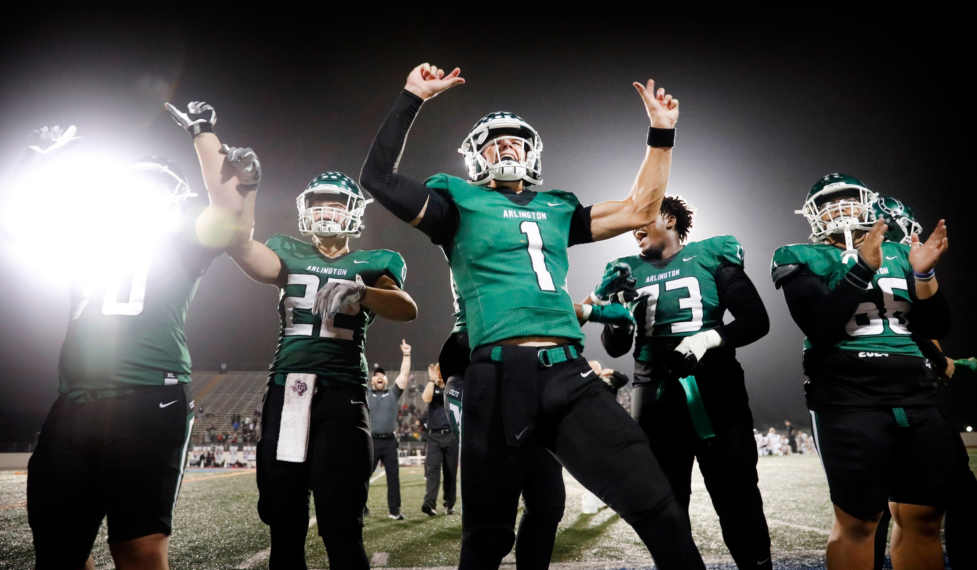 Arlington High quarterback Coleman Cravens (1) and his teammates celebrate their 49-31 win...