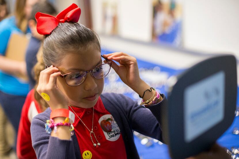 Nayeli Jaramille, 9, tries on different glass frames provided by Essilor Vision Foundation...